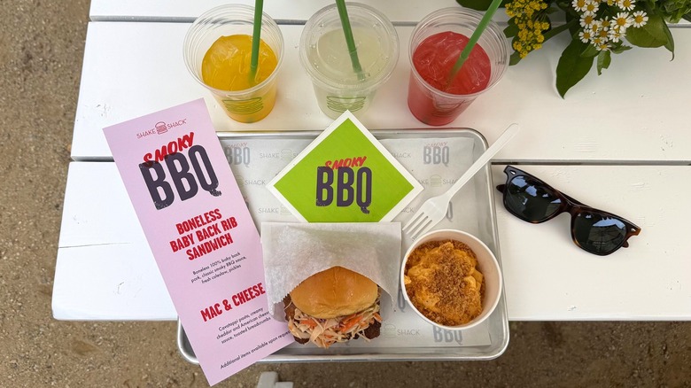 The Shake Shack Smoky BBQ menu on a tray, including a BBQ Boneless Baby Back Rib Sandwich and a Mac & Cheese, surrounded by 3 different lemonades