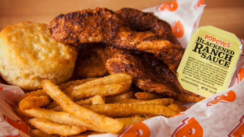 Basket of Popeyes blackened chicken tenders with biscuit, fries, and packet of blackened ranch sauce.