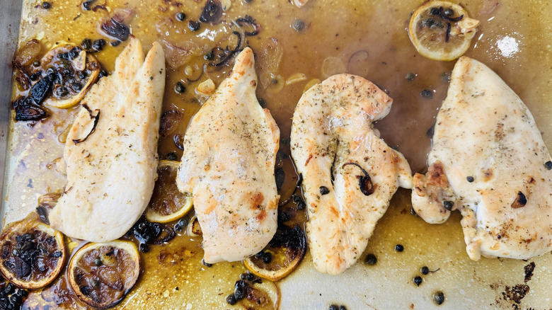 Chicken, sauce, and lemon slices on sheet pan