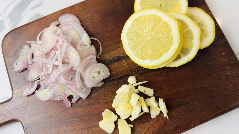 Sliced shallots, garlic, and lemon on wooden board