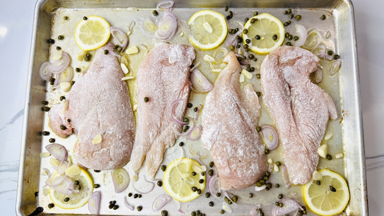 Raw lemony chicken piccata on baking sheet