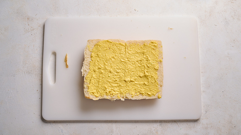 spreading mustard mixture on top buns