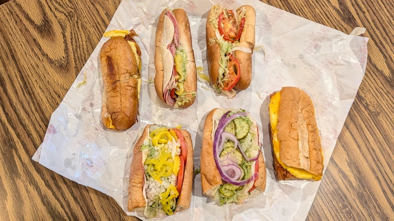 Six small subs from Wawa and Sheetz lined up on wax paper