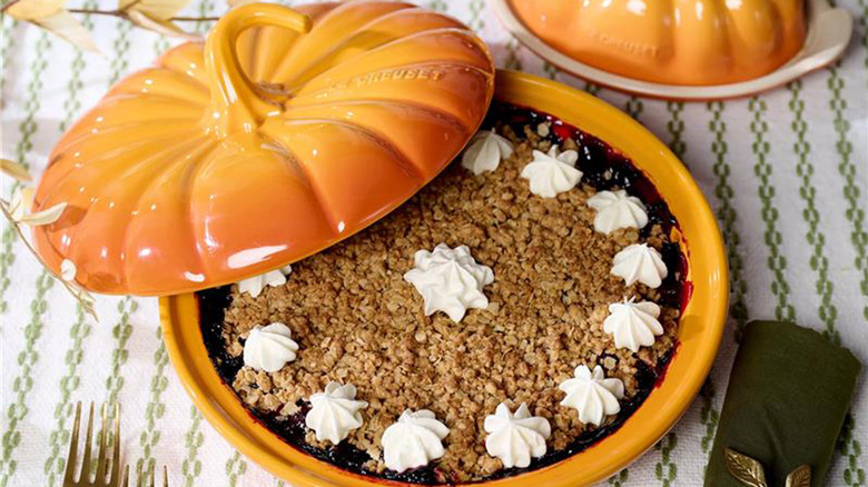 Le Creuset 9 Figural Stoneware Pumpkin Baker w/ Lid displayed on a table with a berry pie inside
