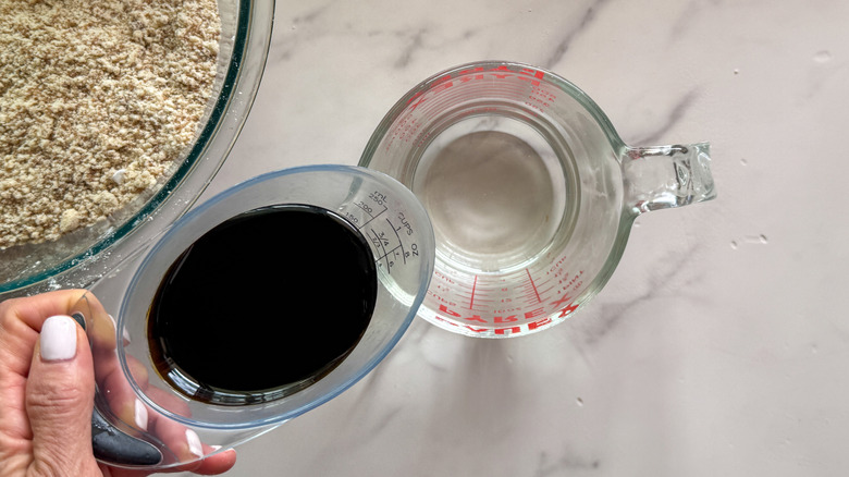 hand adding molasses to water