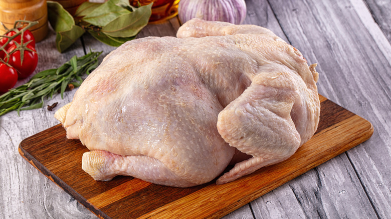 Whole raw chicken on wooden cutting board
