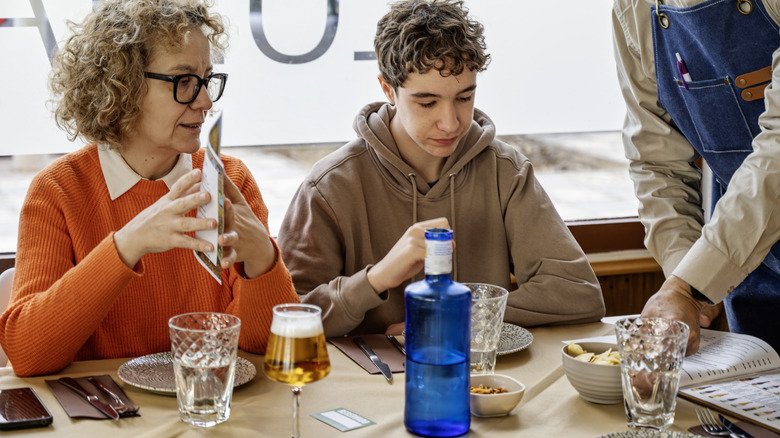 Parent and teenage son at restaurant with alcohol