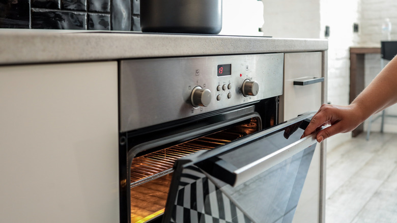 Person opening oven in kitchen