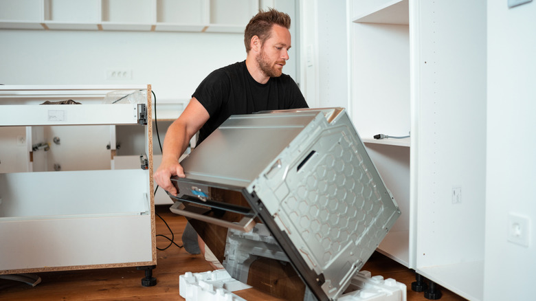 A man in a black shirt installing an oven.