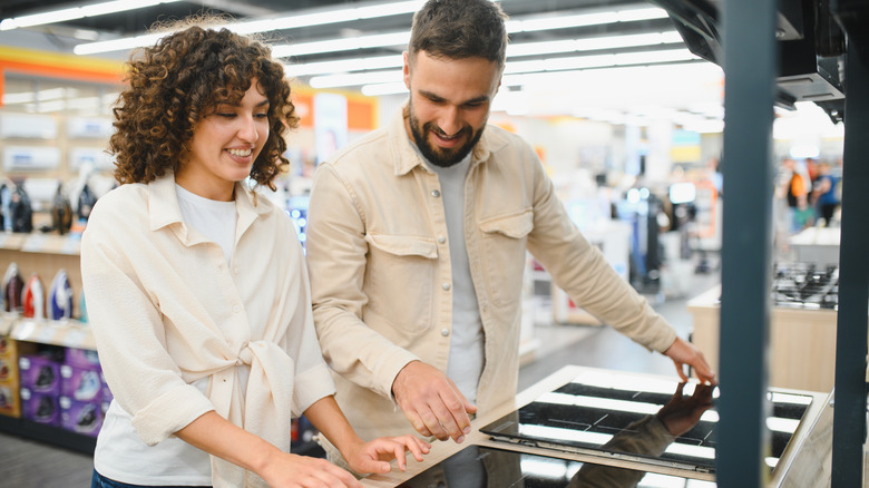 young couple in a retail store, comparing induction cooktop units