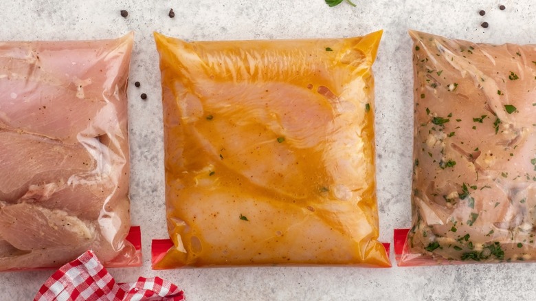 Chicken marinating in sealed freezer bags on countertop.