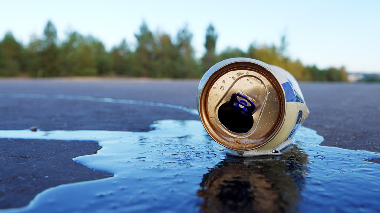 A spilled beer can on the pavement