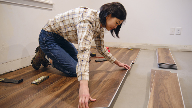 A woman installing luxury vinyl planks in a kitchen