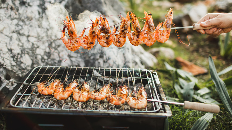 grilled shell-on shrimp on a skewer over a charcoal grill