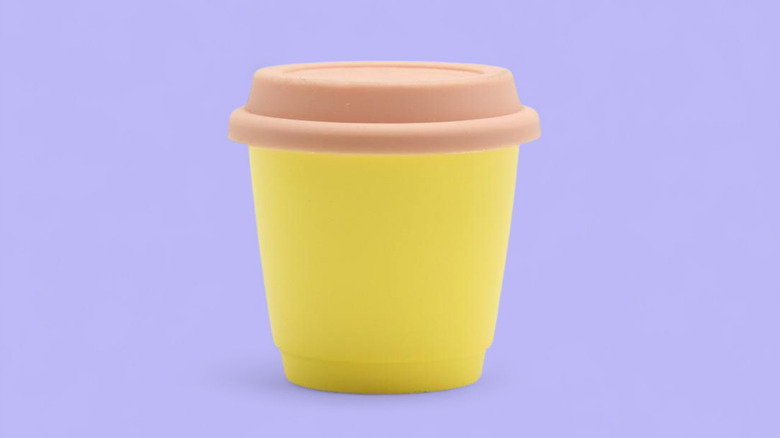 Silicone lid on yellow travel cup on purple background