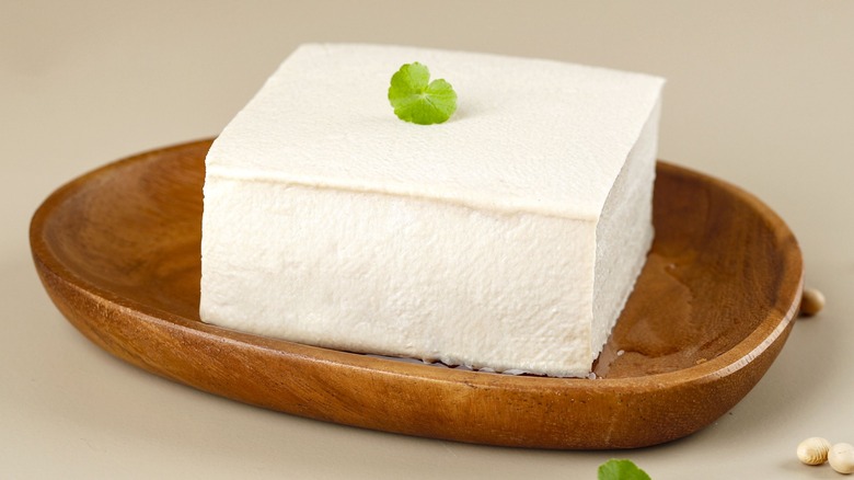A block of silken tofu in a wooden bowl