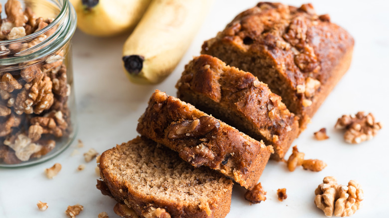 Slices of banana bread next to a jar of walnuts and bananas
