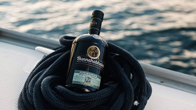 A bottle of Bunnahabhain Stiùiread﻿air﻿ posed inside a coil of rope on a boat