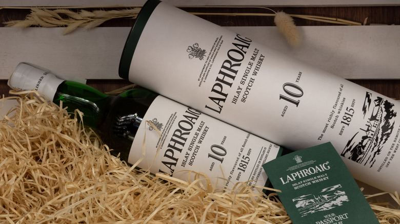A bottle of Laphroaig 10-year and its box laying on top of a pile of straw