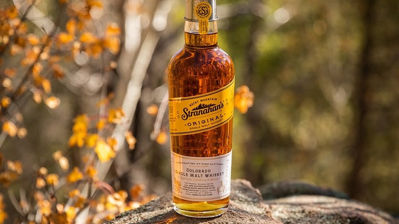 A bottle of Stranahan's Original posed on a rock with a blurred nature background
