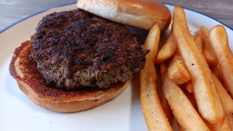 Burger with a bun and fries on a plate from Outback Steakhouse