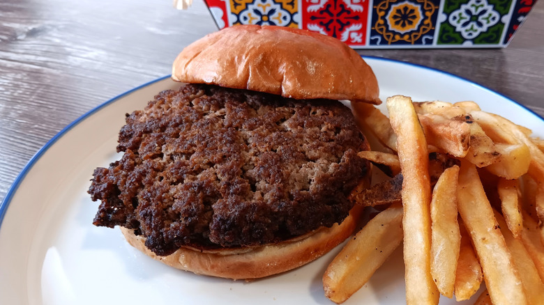 Chili's burger patty on a bun next to fries on a plate