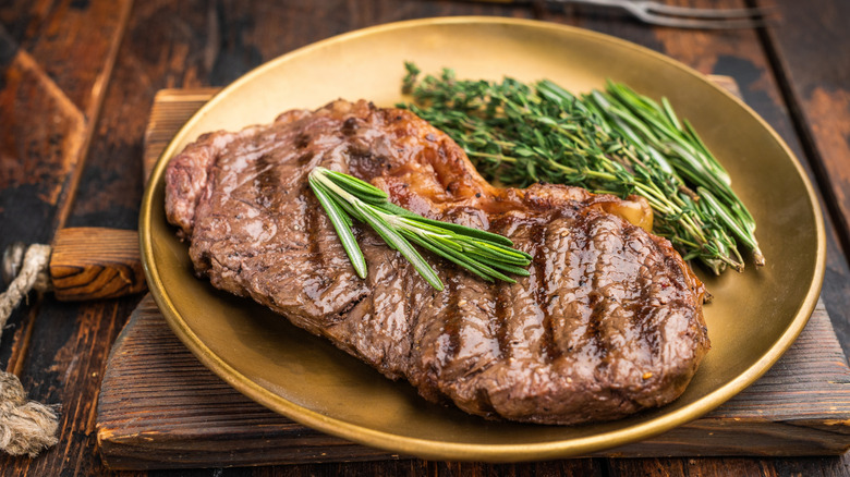 cooked steak on plate with herbs