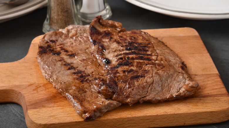 two cooked steaks on wooden cutting board