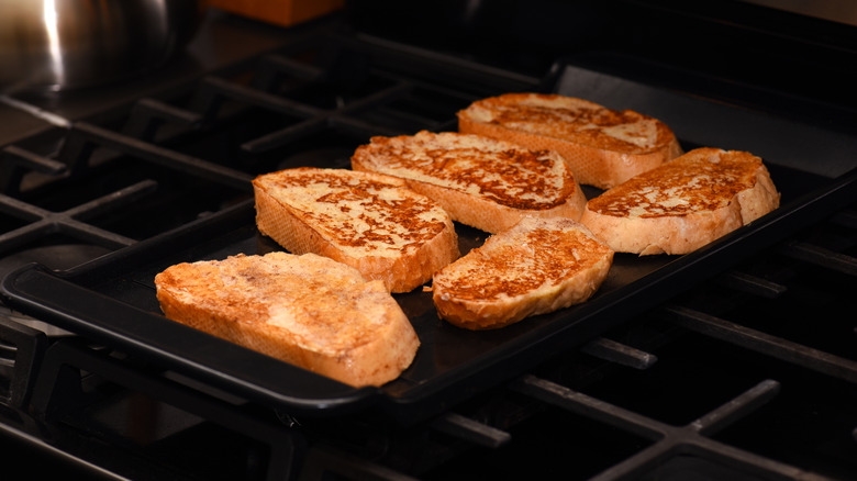 Slices of French toast cooking on a griddle