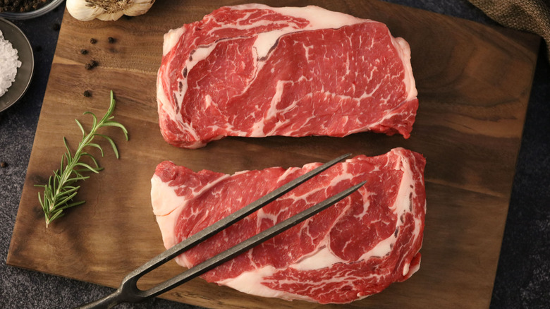 Raw beef steaks on a wood cutting board
