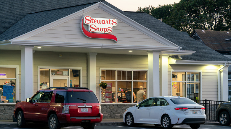 A sedan and an SUV parked in front of a Stewart's during the day