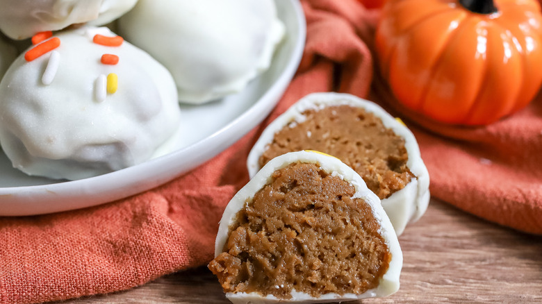 White chocolate pumpkin spice truffles on a plate with one cut open to reveal  the filling inside
