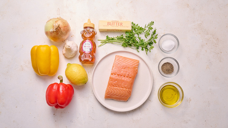 peppers, onion, garlic, lemon, honey, butter, raw salmon and other ingredients on a table
