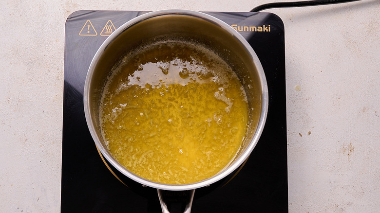 aerial view of garlic cooking in melted butter in a saucepan