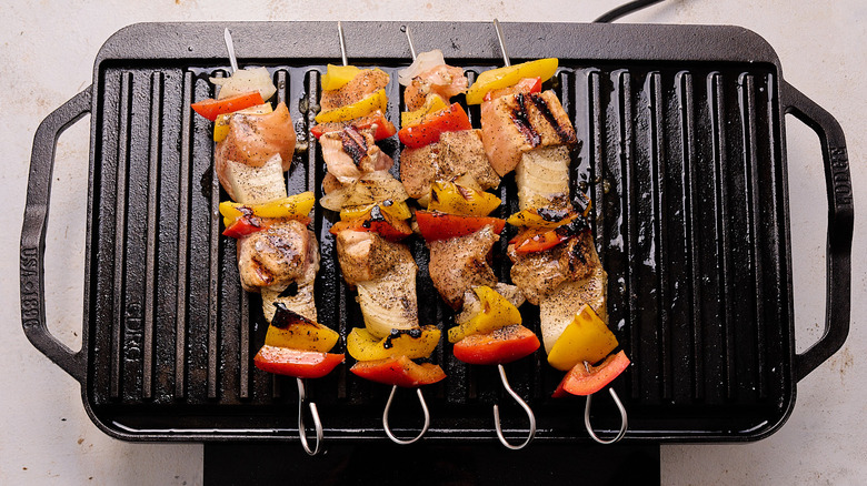 aerial view of four salmon kebabs cooking on a grill