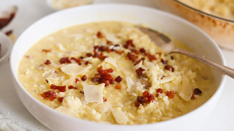 A bowl of creamy carbona-style risotto topped with crispy pancetta pieces and thickly grated parmesan