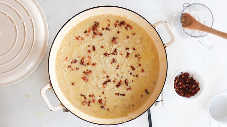 An aerial view of a pot of creamy carbona-style risotto topped with crispy pancetta pieces