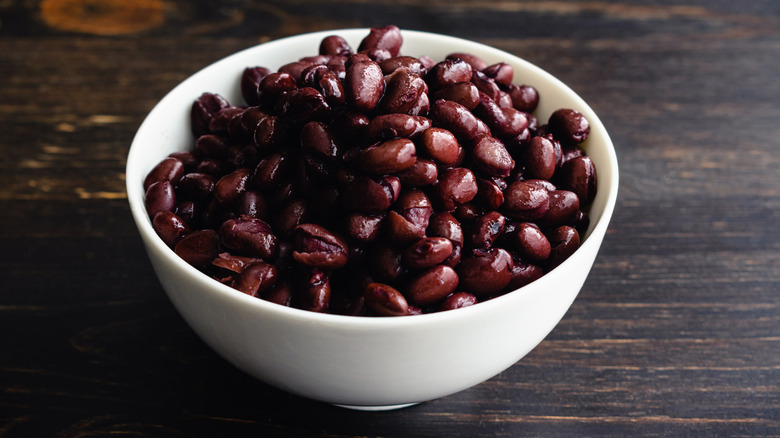 Black beans served in a white bowl on wooden table