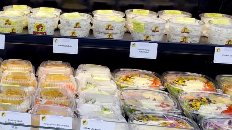 Salads and sandwiches on display inside cold case at Buc-ee's gas station, including cranberry pecan chicken salad