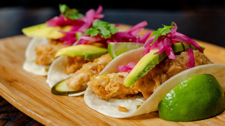 fried fish tacos with avocado slices and onions
