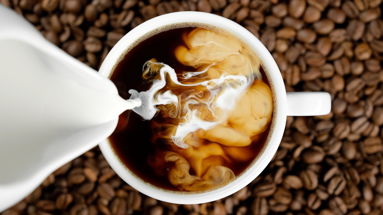 top view of milk being poured into a cup of coffee