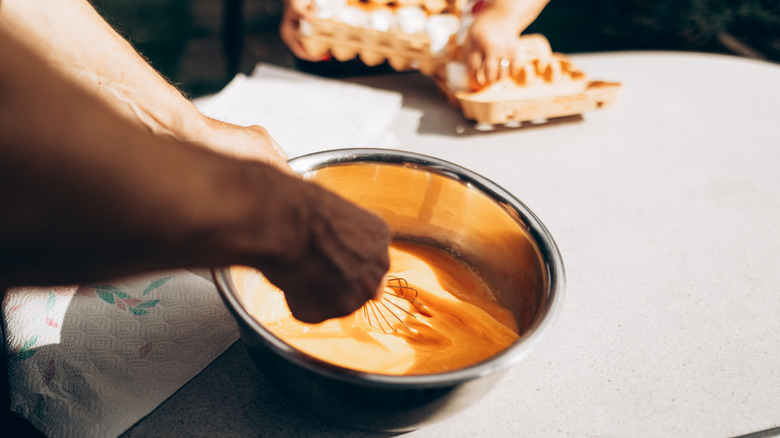 cook mixing eggs in bowl