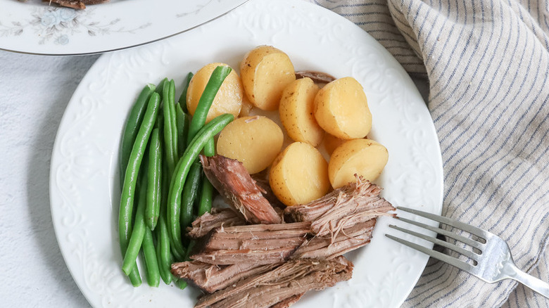 Slow-cooked beef on a plate with boiled potatoes and green beans
