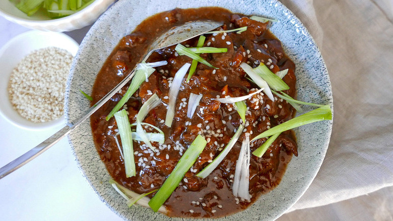 Bowl of slow-cooked beef, garnished with sliced green onion