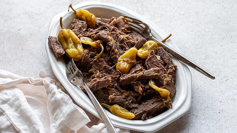 Slow-cooked pulled beef on a plate with pepperoncini peppers