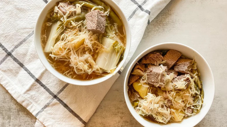 Two bowls of beef sinigang soup with angel hair cabbage