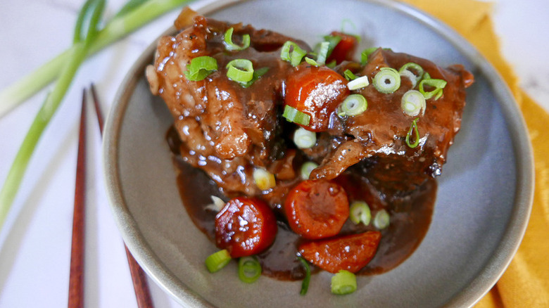 Slow-cooked short ribs on a plate with carrots and green onion