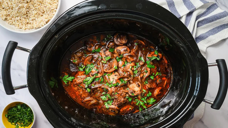 Salisbury steak in a slow cooker, garnished with fresh parsley
