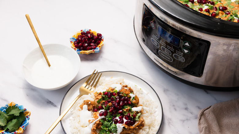 Plate with chicken tikka masa besides slow cooker, yogurt and toppings