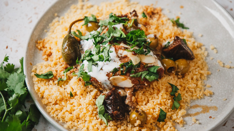 Plate with couscous and chicken thigh with toppings